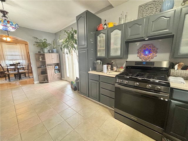 kitchen with stainless steel gas stove, light tile patterned flooring, and decorative light fixtures