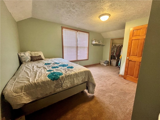 bedroom featuring carpet flooring, a spacious closet, a textured ceiling, vaulted ceiling, and a closet