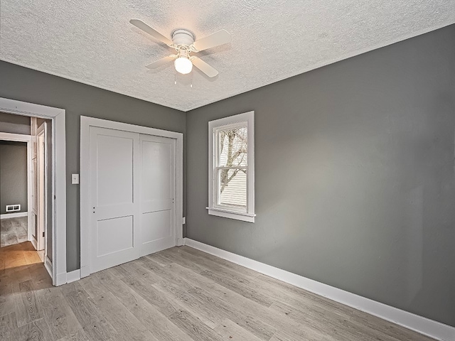 unfurnished bedroom featuring a textured ceiling, light wood-type flooring, a closet, and ceiling fan