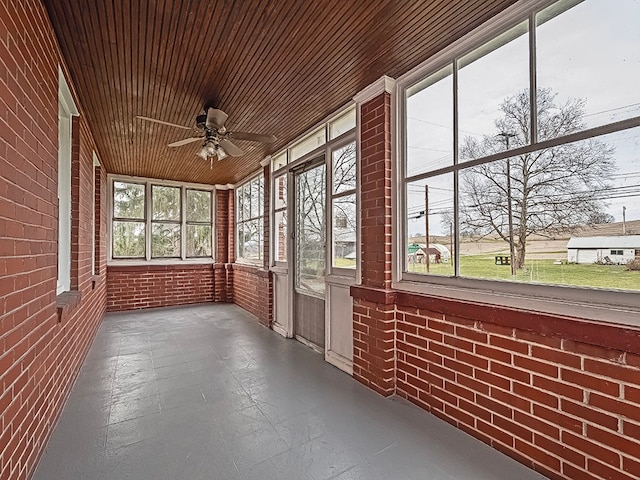 unfurnished sunroom featuring a wealth of natural light, ceiling fan, and wood ceiling