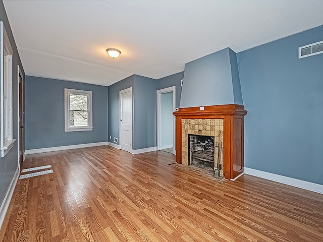 unfurnished living room featuring a tiled fireplace and hardwood / wood-style flooring