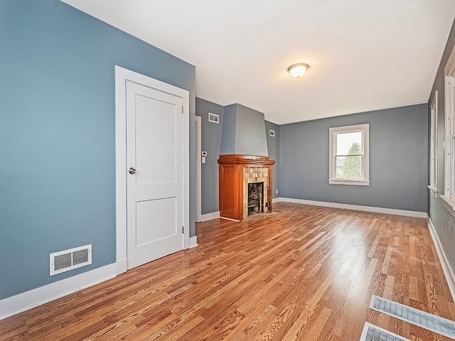 unfurnished living room with hardwood / wood-style flooring and a tiled fireplace