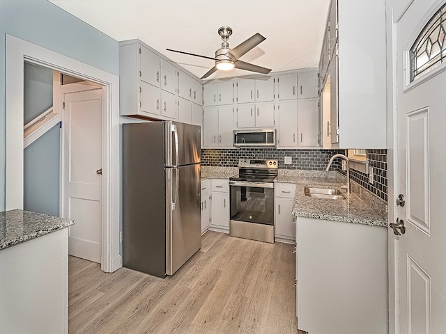 kitchen featuring white cabinets, appliances with stainless steel finishes, light hardwood / wood-style flooring, and light stone countertops