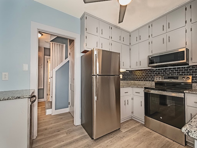 kitchen with decorative backsplash, appliances with stainless steel finishes, light hardwood / wood-style floors, and white cabinetry