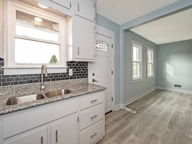 kitchen with a healthy amount of sunlight, sink, white cabinetry, and backsplash