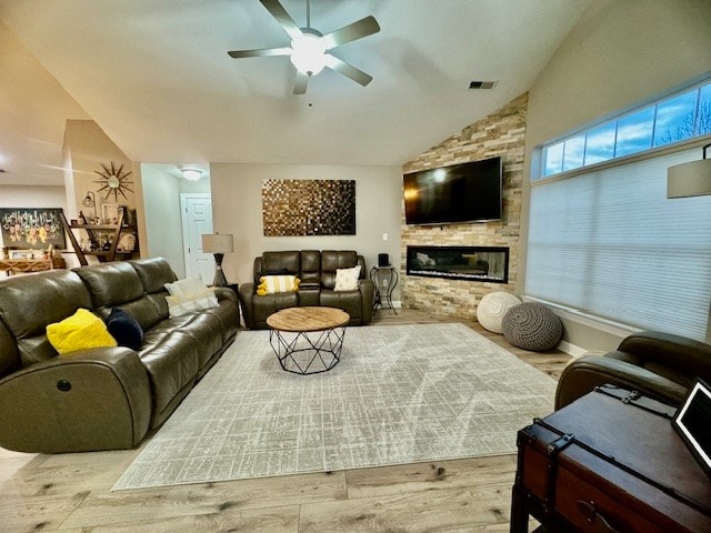 living room with a fireplace, ceiling fan, light hardwood / wood-style flooring, and vaulted ceiling