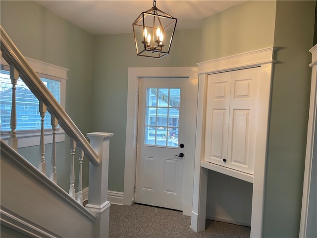 carpeted foyer with an inviting chandelier