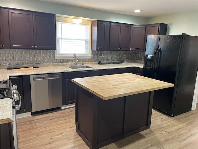 kitchen with light wood-type flooring, stainless steel appliances, a kitchen island, and sink