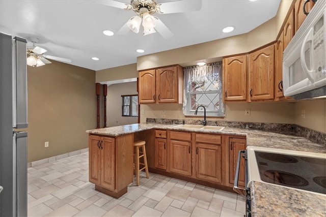 kitchen with kitchen peninsula, ceiling fan, sink, and white appliances