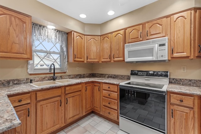 kitchen with light stone countertops, white appliances, and sink