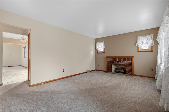 unfurnished living room featuring ceiling fan, carpet, and a brick fireplace