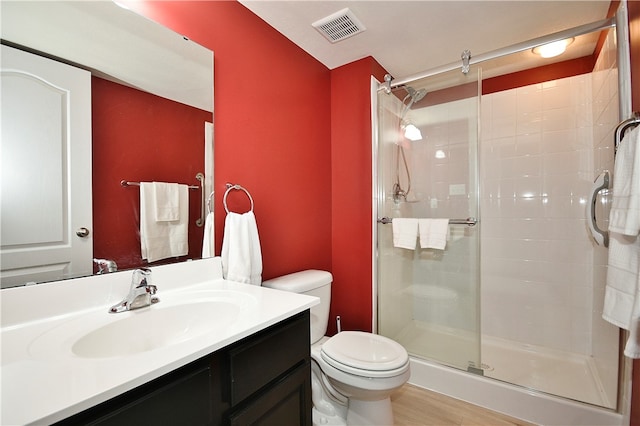 bathroom with hardwood / wood-style floors, vanity, a shower with shower door, and toilet