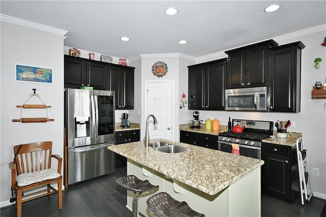 kitchen with light stone countertops, sink, stainless steel appliances, a breakfast bar area, and a kitchen island with sink