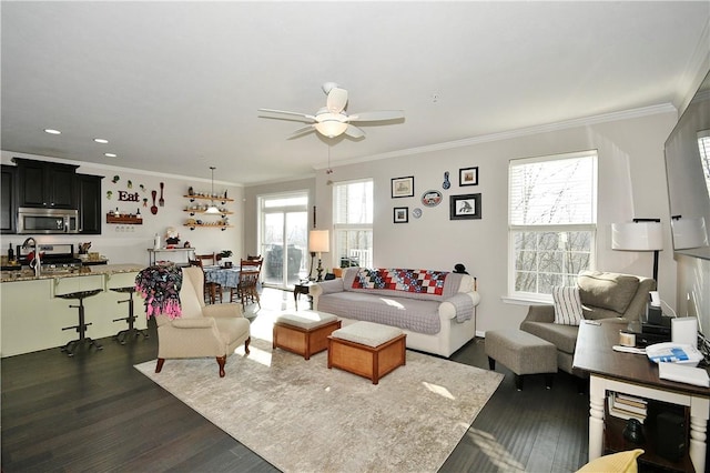 living room with ornamental molding, dark wood-type flooring, ceiling fan, and a healthy amount of sunlight