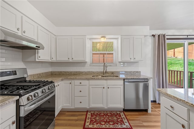 kitchen with white cabinets, appliances with stainless steel finishes, light hardwood / wood-style floors, and sink