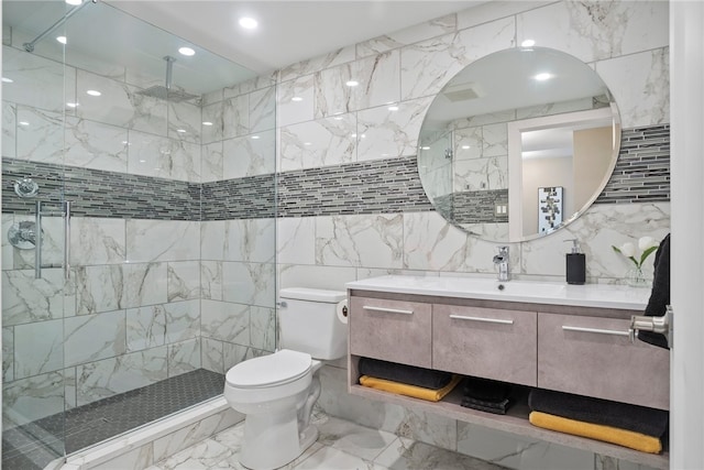 bathroom with tiled shower, vanity, toilet, and tile walls