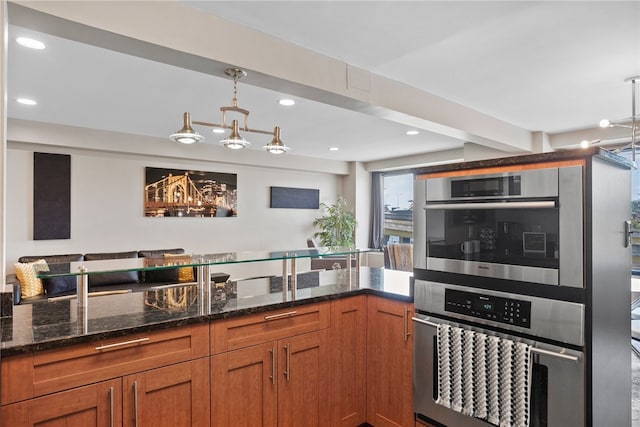 kitchen featuring pendant lighting, stainless steel double oven, and dark stone counters