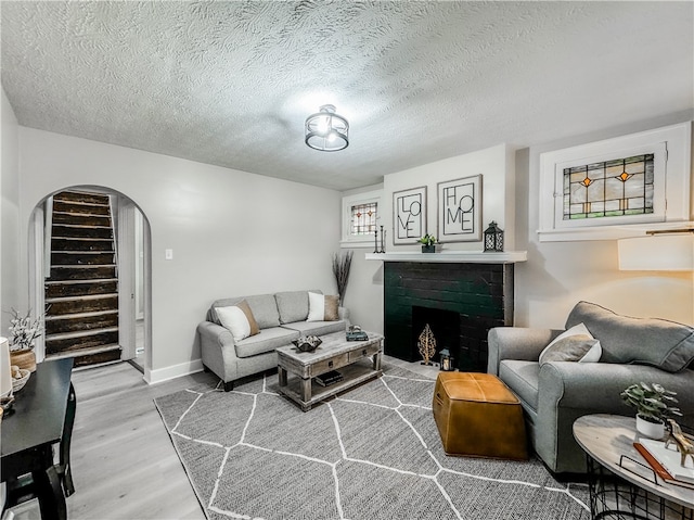 living room with light hardwood / wood-style floors, a textured ceiling, and a brick fireplace