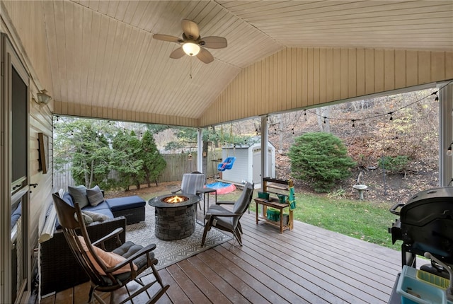 wooden deck with a storage unit, grilling area, and an outdoor living space with a fire pit