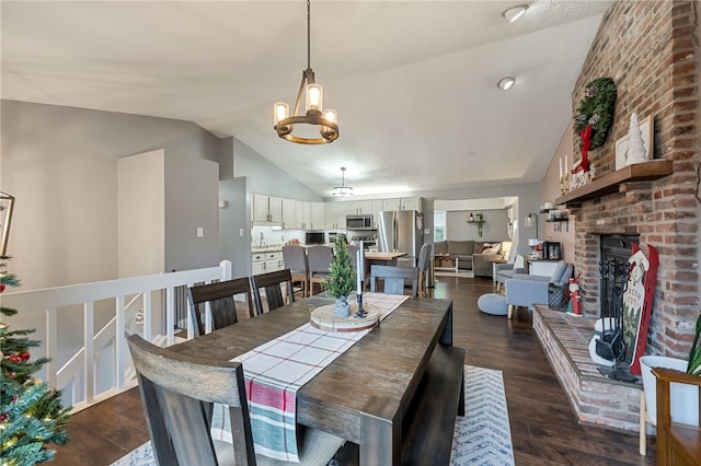 dining room with sink, a brick fireplace, dark hardwood / wood-style floors, a chandelier, and lofted ceiling