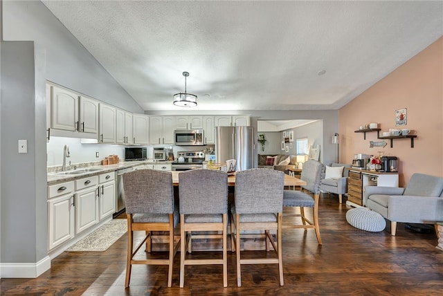 kitchen with sink, dark wood-type flooring, vaulted ceiling, and appliances with stainless steel finishes