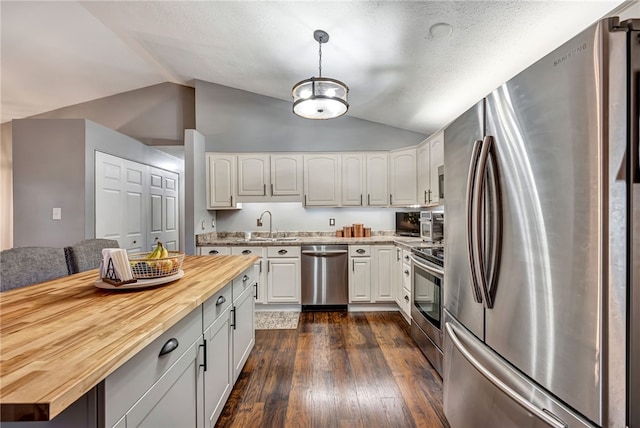 kitchen featuring wooden counters, white cabinets, stainless steel appliances, and lofted ceiling