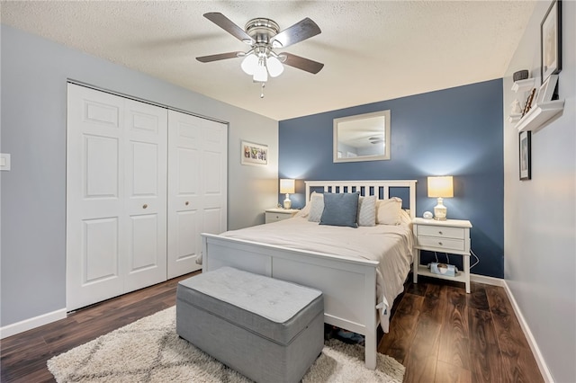 bedroom with ceiling fan, dark hardwood / wood-style floors, a textured ceiling, and a closet