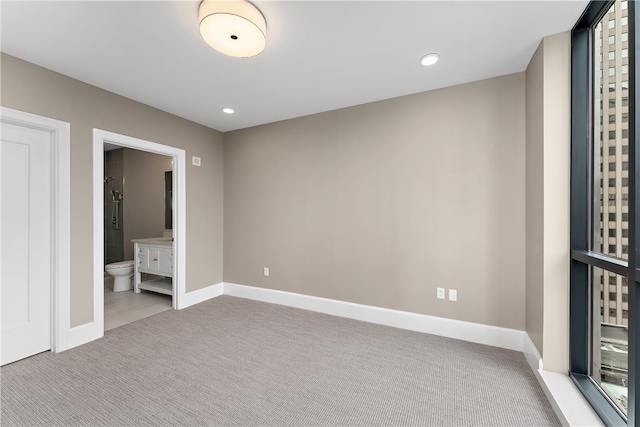 unfurnished bedroom with connected bathroom and light colored carpet