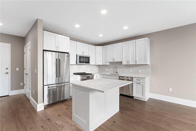 kitchen featuring a center island, sink, appliances with stainless steel finishes, white cabinets, and hardwood / wood-style flooring