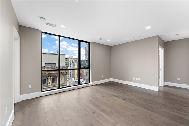 unfurnished room featuring expansive windows and hardwood / wood-style flooring