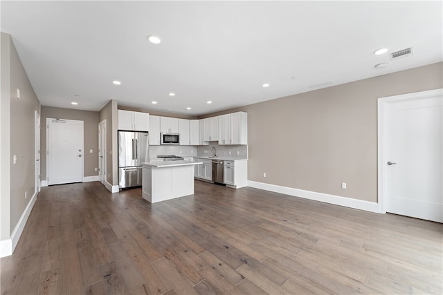 kitchen with appliances with stainless steel finishes, sink, hardwood / wood-style flooring, a center island, and white cabinetry