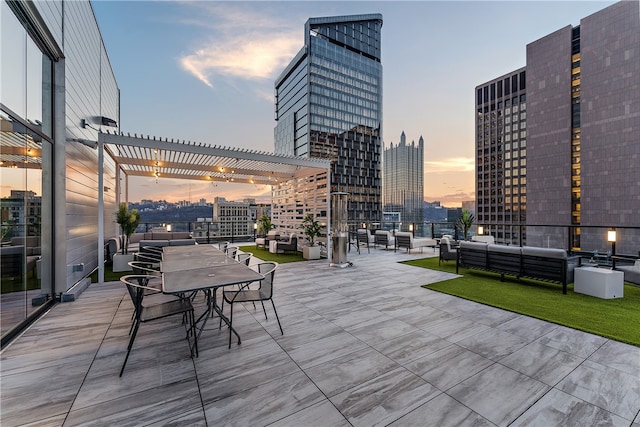 patio terrace at dusk with outdoor lounge area and a pergola