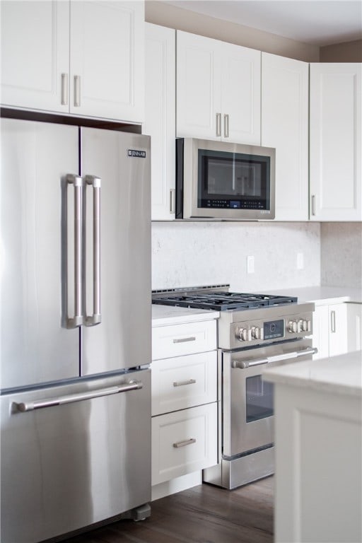 kitchen featuring white cabinets, dark hardwood / wood-style floors, tasteful backsplash, and high end appliances