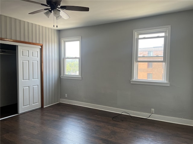 unfurnished bedroom with dark hardwood / wood-style floors, a closet, multiple windows, and ceiling fan