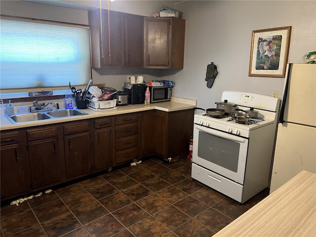 kitchen with dark brown cabinetry, sink, and white appliances