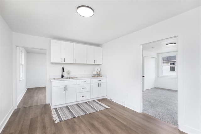 bar featuring white cabinets, sink, and hardwood / wood-style flooring