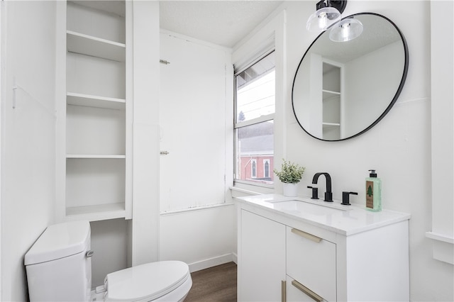 bathroom with vanity, toilet, wood-type flooring, and a textured ceiling