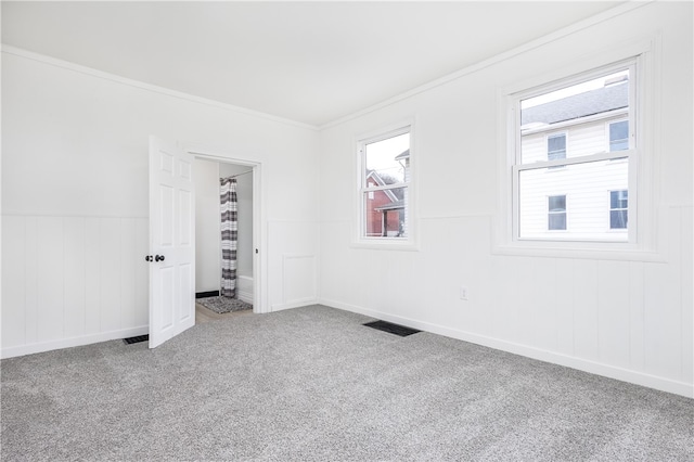 carpeted empty room featuring crown molding and a healthy amount of sunlight