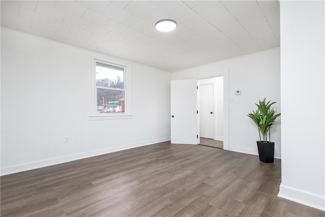 unfurnished room featuring ornamental molding and dark wood-type flooring