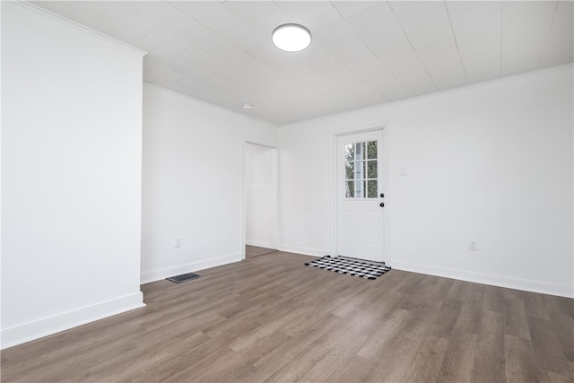 empty room featuring crown molding and wood-type flooring