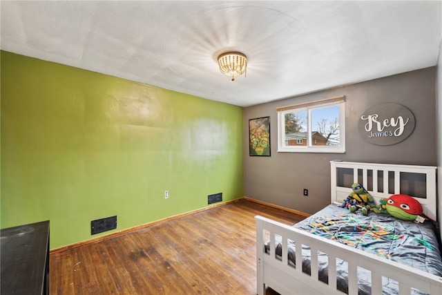 bedroom featuring a chandelier and hardwood / wood-style floors