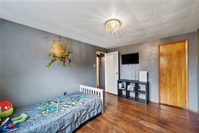 bedroom featuring a chandelier and dark wood-type flooring