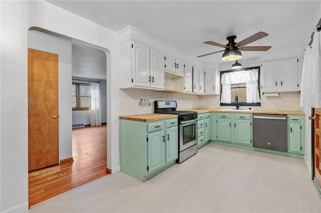 kitchen featuring ceiling fan, white cabinetry, stainless steel appliances, light hardwood / wood-style flooring, and backsplash