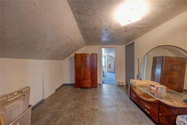 bathroom with hardwood / wood-style floors, lofted ceiling, and a textured ceiling