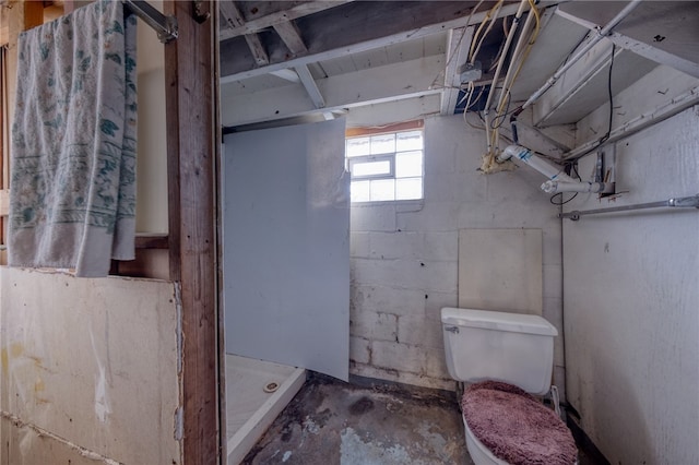 bathroom with a shower, concrete floors, and toilet