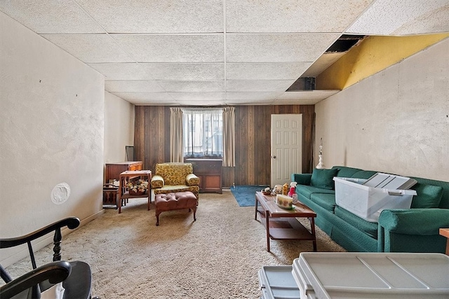 interior space with carpet flooring, wood walls, and a drop ceiling