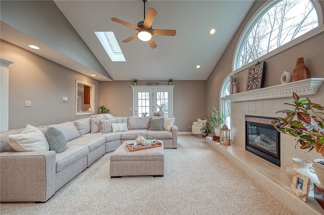 carpeted living room featuring a tiled fireplace, ceiling fan, french doors, and high vaulted ceiling