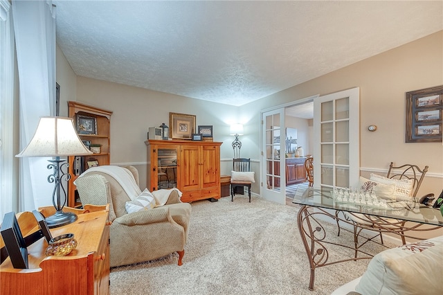 carpeted living room with french doors and a textured ceiling