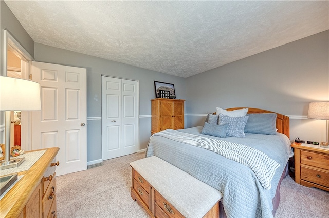 bedroom featuring light carpet, a closet, and a textured ceiling