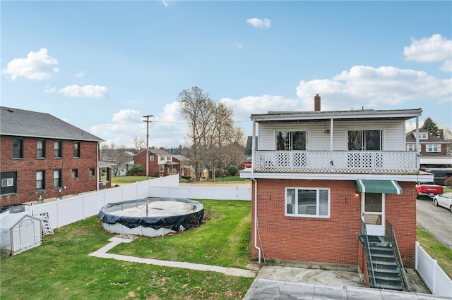 back of house featuring a covered pool and a lawn